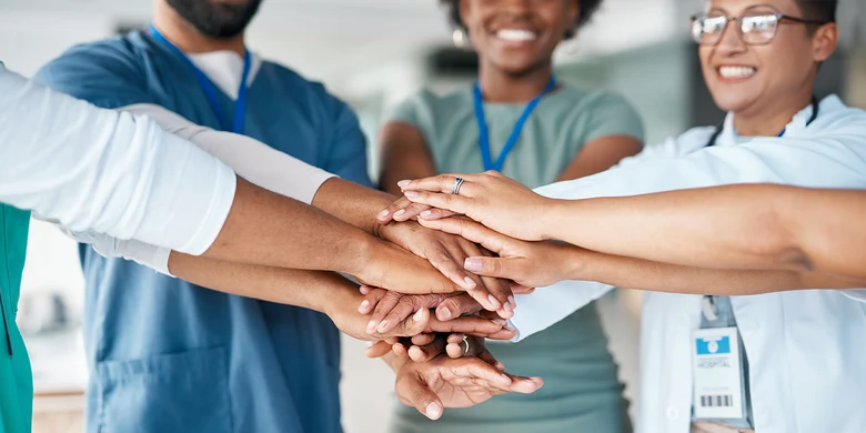 Medizinisches Team legt Hände übereinander als Zeichen des Zusammenhalts. Teamarbeit im Gesundheitswesen.