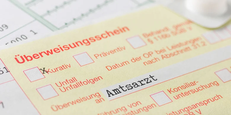Gelber Überweisungsschein mit Ankreuzfeldern für kurativ, präventiv und Unfallfolgen sowie Überweisung an Amtsarzt und konsiliarärztliche Untersuchung.