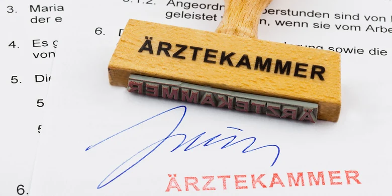 Holzstempel mit Aufschrift „ÄRZTEKAMMER" auf Dokument mit Unterschrift und Stempelabdruck.