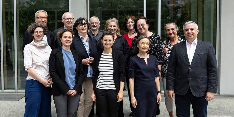 Gruppenfoto der Mitglieder der Sächsischen Impfkommission vor Gebäude. 14 Personen in Geschäftskleidung.